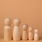 pexels photo 38514870 38514870 Five wooden peg figures arranged in size order on a neutral beige background.